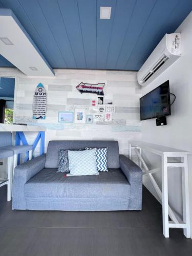 a living room with a couch and a tv on a wall at Crusoe Cabins Casobe in Calatagan