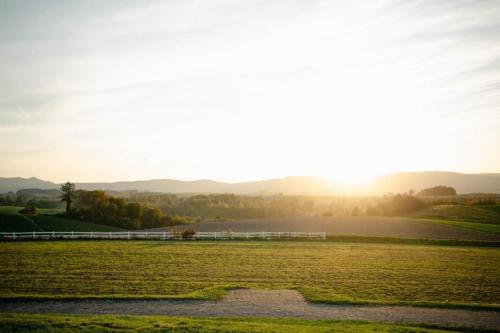 a field with the sun setting in the background at 青い池まで車で20分Biei Breeze Reserve in Biei
