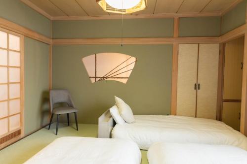 a bedroom with two beds and a chair in it at 青い池まで車で20分Biei Breeze Reserve in Biei