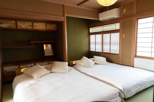 two beds in a room with two windows at 青い池まで車で20分Biei Breeze Reserve in Biei