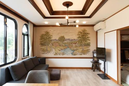 a living room with a couch and a painting on the wall at 青い池まで車で20分Biei Breeze Reserve in Biei