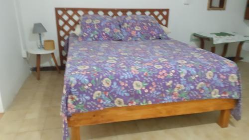 a bed with a purple comforter with a wooden frame at Leu Océans in Saint-Leu
