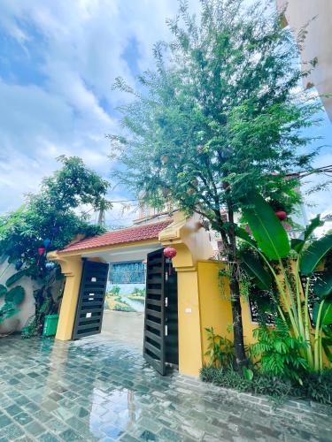 a yellow building with a tree in front of it at La Mai Tam Coc Homestay in Ninh Binh