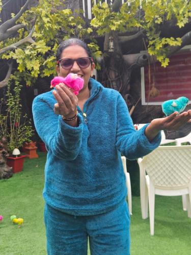 a woman is holding a pink stuffed animal at S & B Dreams House in Munnar