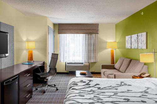 a hotel room with a bed and a desk and a couch at Sleep Inn & Suites Harbour Pointe in Brandermill