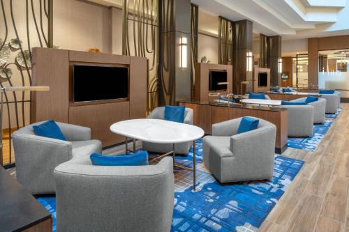 a lobby with chairs and a table and a tv at Madison Marriott West in Middleton