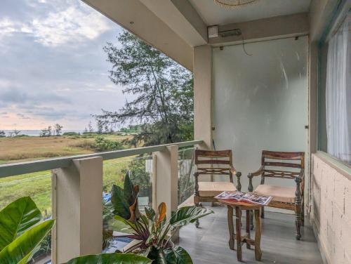 two chairs on a balcony with a view of a field at Beach Villa Morjim in Morjim