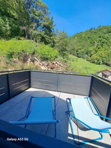 two blue chairs sitting on a patio with a fence at B&B Val Maschi in Lamon