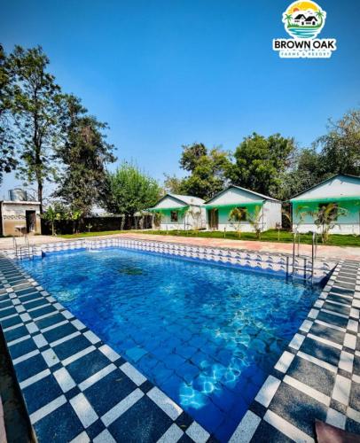 a swimming pool at a resort with blue water at Brown Oak Farms in Sohna