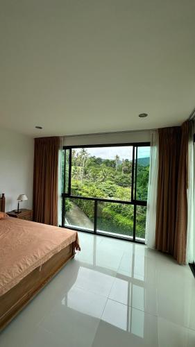 a bedroom with a bed and a large window at Apartment in Koh Samui