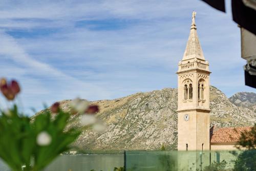 a church steeple with a clock tower in front of a mountain at Alla Cartolina in Kotor