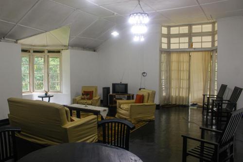 a living room with yellow chairs and a tv at HEYCOCK CEYLON HlLL in Gampola