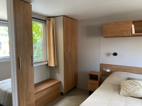 a small bedroom with a bed and a window at Mobile home cocon in Lège-Cap-Ferret