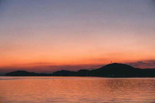 a sunset over a body of water with mountains at 糸島STAYｘCafe 海のみちひき-小富士あたり- in Itoshima