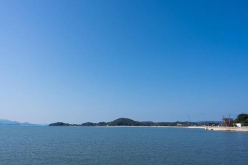 a large body of water with a beach in the background at 糸島STAYｘCafe 海のみちひき-小富士あたり- in Itoshima