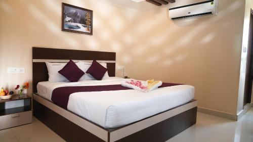 a bedroom with a large bed with white sheets and purple pillows at Hotel Mountview Comforts in Tirupati