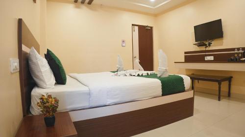 a bedroom with a bed with white sheets and a television at Hotel Mountview Comforts in Tirupati