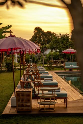a row of chairs and umbrellas next to a pool at Umah Lusa in Munduk