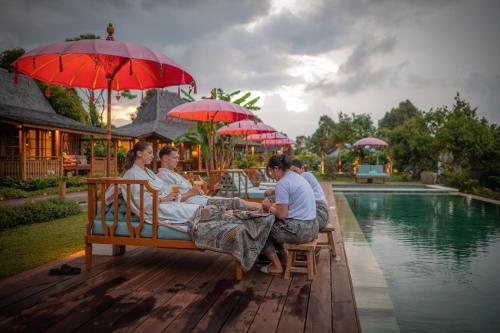 a group of people sitting on a bench next to a pool at Umah Lusa in Munduk