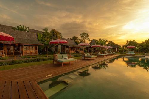 a pool with chairs and umbrellas next to a building at Umah Lusa in Munduk