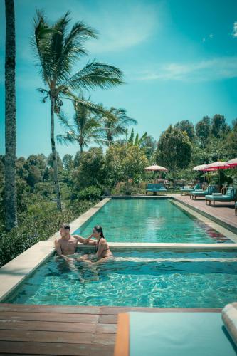 two people in a swimming pool at a resort at Umah Lusa in Munduk