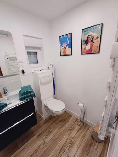 a white bathroom with a toilet and a sink at Au Petit Nid in Bergues