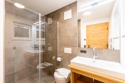 a bathroom with a sink and a shower and a toilet at Tauernlodges Uttendorf by ALPS RESORTS in Uttendorf