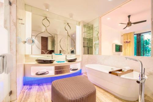 a bathroom with a tub and a large mirror at W Goa in Vagator