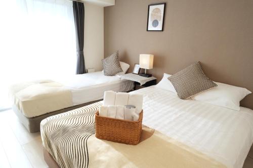 a hotel room with two beds and a chair at Sanctuary Residence TennojiKouenMinami in Osaka
