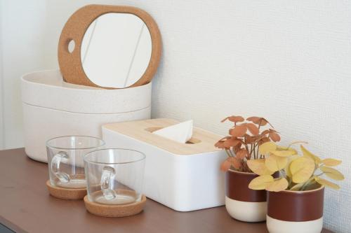a table with two glasses and a mirror and plants at Sanctuary Residence TennojiKouenMinami in Osaka