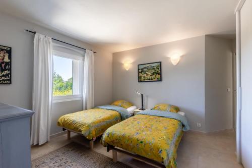 deux lits dans une chambre avec une fenêtre dans l'établissement Li Cigalo, à Bonnieux