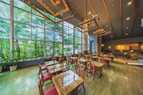 a restaurant with tables and chairs and large windows at Onsen & Stay OAKHILL in Zao Onsen