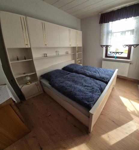 a bedroom with a bed and cabinets and a window at Ferienwohnung am Hammerberg in Schönheide