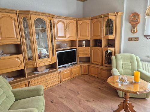 a living room with wooden cabinets and a tv at Ferienwohnung am Hammerberg in Schönheide