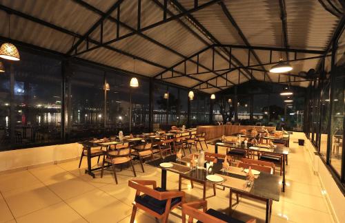 a restaurant with wooden tables and chairs and windows at RiverView Tent Resort in Kevadia