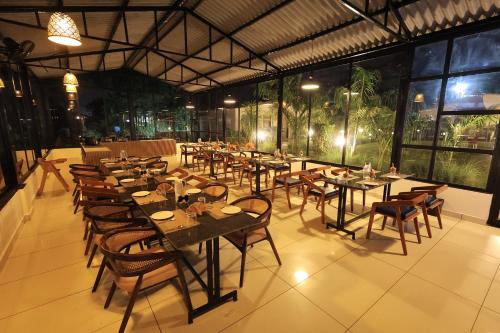 an empty restaurant with tables and chairs and windows at RiverView Tent Resort in Kevadia