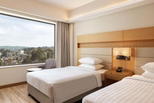 a hotel room with two beds and a large window at Courtyard by Marriott Shillong in Shillong