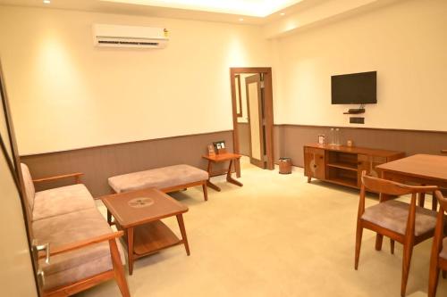 a waiting room with chairs and a tv and tables at Hotel Sonar Bangla Tarapith in Tarapith