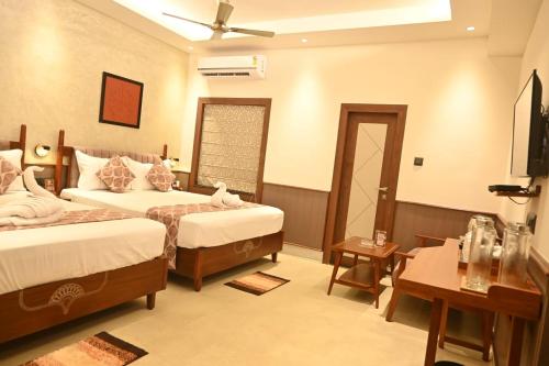 a hotel room with two beds and a television at Hotel Sonar Bangla Tarapith in Tarapith