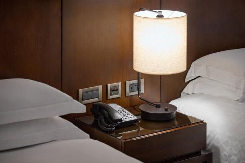 a bedroom with a phone on a nightstand next to a bed at Sheraton Grand Taipei Hotel in Taipei