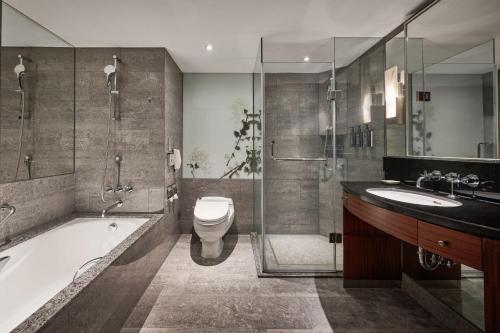a bathroom with a tub and a toilet and a sink at Sheraton Grand Taipei Hotel in Taipei