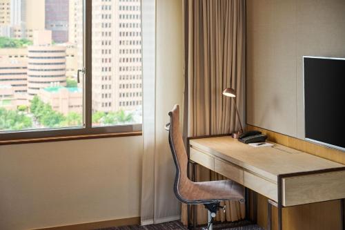a room with a desk with a television and a chair at Sheraton Grand Taipei Hotel in Taipei