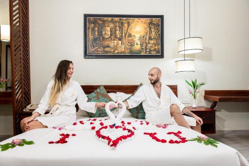 a man and woman in white robes sitting on a bed at Bayon Modern Residence in Siem Reap