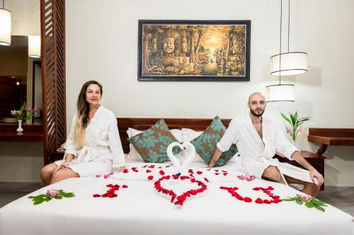 a man and a woman sitting on a bed at Bayon Modern Residence in Siem Reap