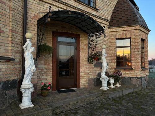 two statues in front of a building with a door at Villa Vesta in Dolnāja