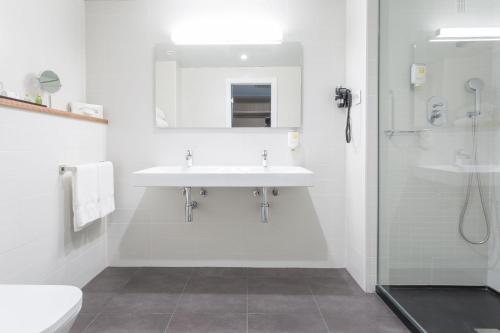 a white bathroom with a sink and a shower at ARTIEM Madrid in Madrid