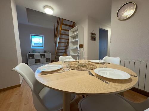 - une table en bois avec des assiettes et des chaises blanches dans l'établissement Tranquillité, à Rountzenheim