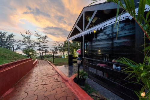 a house with a brick walkway next to a building at TT Beach Cottages in Candolim