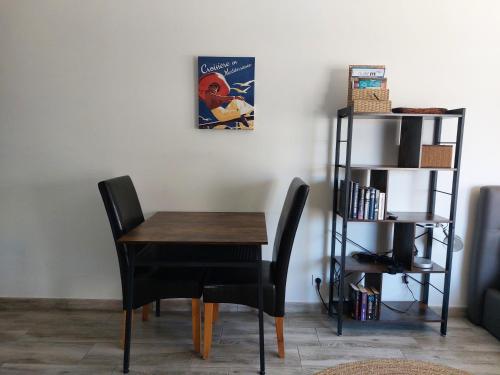 une table à manger avec deux chaises et une étagère. dans l'établissement Sur la plage, super studio avec vue sur la mer, à Plage dʼArgelès