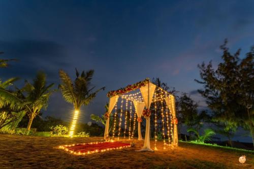 a tent with lights on the beach at night at TT Beach Cottages in Candolim